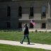 A man walks with an American flag during "Operation Haircut", a protest put on by supporters of the Michigan Conservative Coalition at the state capitol, after barber Karl Manke had his license suspended for violating the coronavirus disease (COVID-19) re