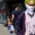 A man wears a piece of cloth as a protective mask as he walks down a street following the coronavirus disease (COVID-19) outbreak, in Ilford, London, Britain July 29, 2020. REUTERS/Hannah McKay