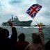 People wave as the flagship of Britain's Royal Navy HMS (Her Majesty's Ship) Ark Royal approaches Portsmouth Harbour on the coast of southern England, after operations in the Gulf conflict, May 17, 2003. REUTERS/Michael Crabtree