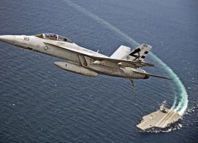 An F/A-18F Super Hornet assigned to Air Test and Evaluation Squadron (VX) 23 flies over the aircraft carrier USS Gerald R. Ford (CVN 78). The aircraft carrier is underway conducting test and evaluation operations.